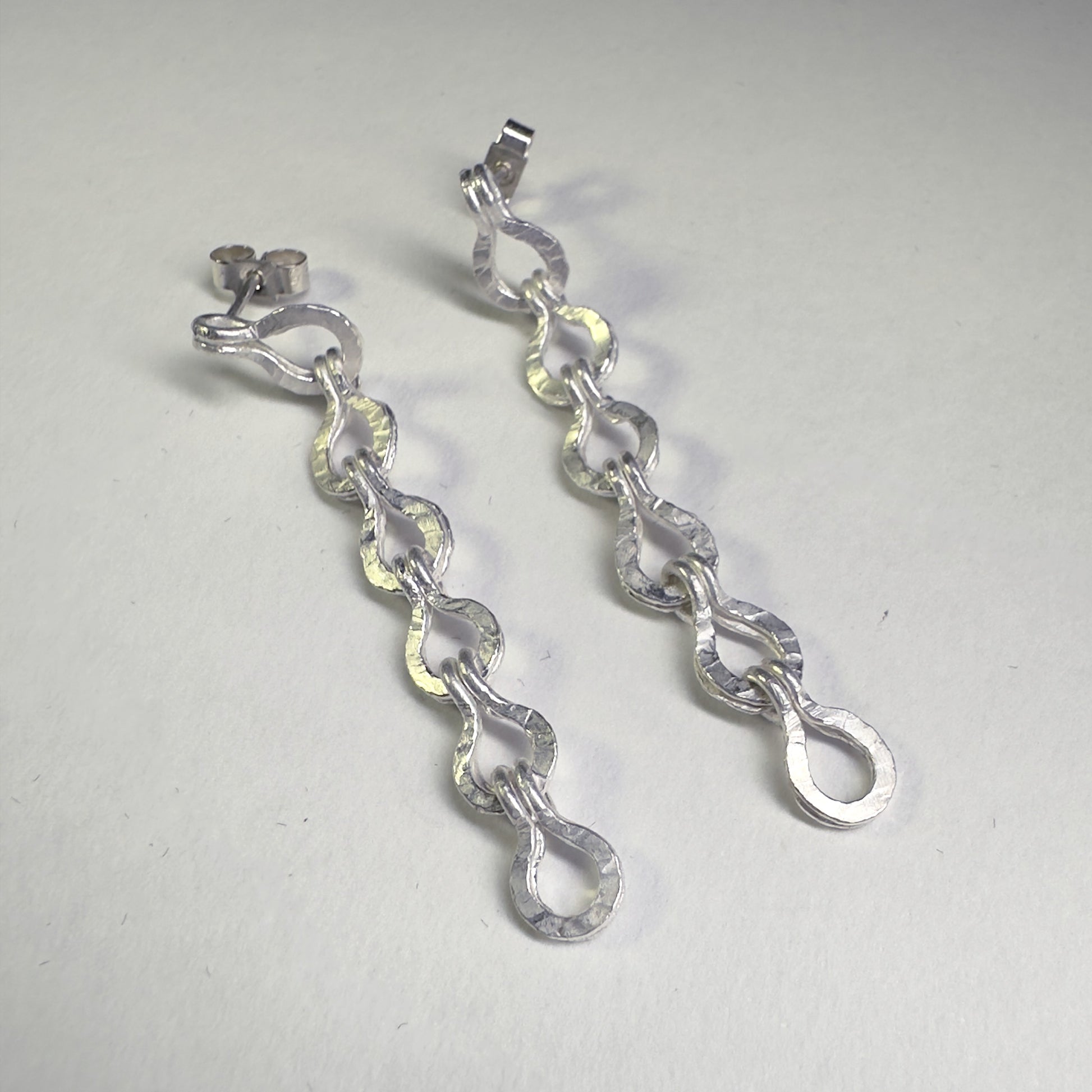 Silver roman chain drop earrings with white background